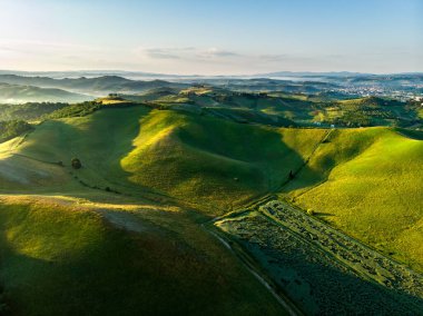 Ufukta küçük köyleri olan tarlaları ve tarlaları sabah görüşü göz kamaştırıcı. İtalya, Toskana 'nın kayan tepeleri, kıvrımlı yolları ve selvilerinin yaz manzarası.