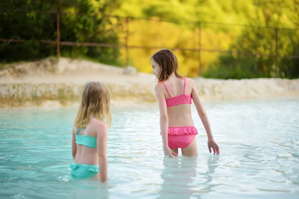 2人の若い姉妹は 白のコンクリートと滝を形成する温泉水と炭酸カルシウム鉱床で Bagno Vignoniの天然スイミングプールで入浴します イタリアのトスカーナ州 — ストック写真