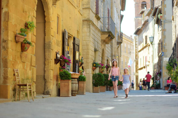 Young sisters exploring in Pienza, a village located in the beautiful Tuscany valley, known as the 'ideal city of the Renaissance' and a 'capital' of pecorino cheese. UNESCO World Heritage Site.