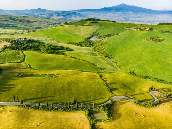 地平線に小さな村と緑のフィールドや農地の見事な空中ビュー 丘陵の夏の農村風景 トスカーナの湾曲した道路やヒノキ イタリア — ストック写真