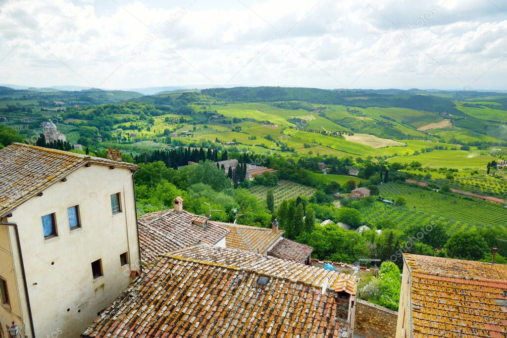 Green hills and pastures of Tuscany and rooftops of Montepulciano town, located on top of a limestone ridge surrounded by vineyards. Vino Nobile wine territory. Tuscany, Italy.
