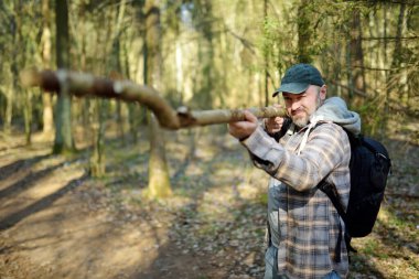 Yakışıklı genç adam güneşli bir bahar gününde ormanda yürüyüş yaparken eğleniyor. Baharda doğayı keşfetmek.
