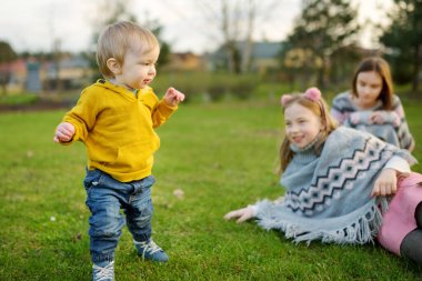 İki abla ve küçük erkek kardeşleri dışarıda eğleniyorlar. Yaz günü iki genç kız ve bir erkek bebek. Geniş yaş farkı olan çocuklar. Kardeşler arasında büyük yaş farkı var. Büyük aile..