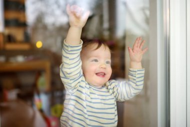Evinin penceresinden bakan sevimli bir çocuk. Küçük çocuk dışarı bakıyor..