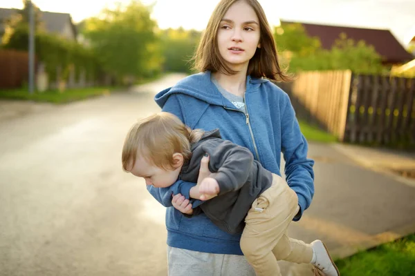 可爱的姐姐抱着她蹒跚学步的弟弟 可爱的少女抱着男婴年龄差距大的儿童 兄弟姐妹之间的年龄差异很大 大家庭 — 图库照片