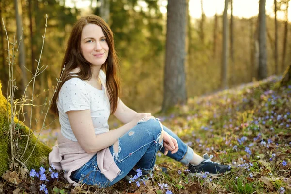 春日的艳阳天 美丽的年轻女子坐在绽放着野草花的地面上 森林里美丽的蓝色春花 大自然的美丽 — 图库照片