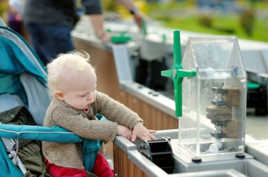 Bebek arabasında, Madurodam minyatür parkında su barajı simülasyonu yapan tatlı bir kız bebek. Lahey, Hollanda.