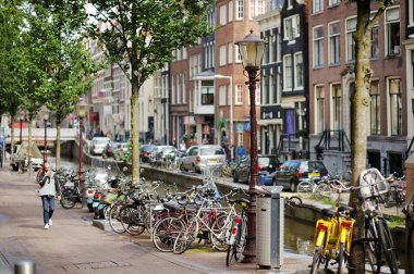 AMSTERDAM - AĞUSTUSTOS 2011: Hollanda 'nın ünlü kanalları. Arabalar ve bisikletler setin üzerine park edilmiş. Amsterdam, Hollanda 'da tipik sokak manzarası.