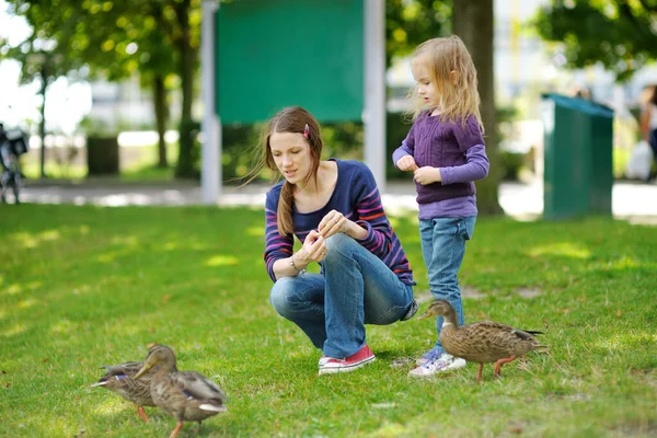 年轻的母亲和她的小女儿在喂鸭子 在户外喂小鸟 幼儿暑期活动 — 图库照片