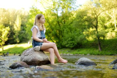 Adorable young girl having fun during a hike in the woods on beautiful sunny summer day. Active family leisure with kids. Kid exploring nature.