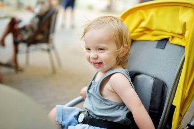 Dışarıda bir bebek arabasında oturan tatlı bir çocuk. Bebek arabasındaki küçük çocuk. Bebek bebek sandalyede oturuyor. Çocuklarla yaz yürüyüşleri. Küçük çocukla ailecek vakit geçirmek..