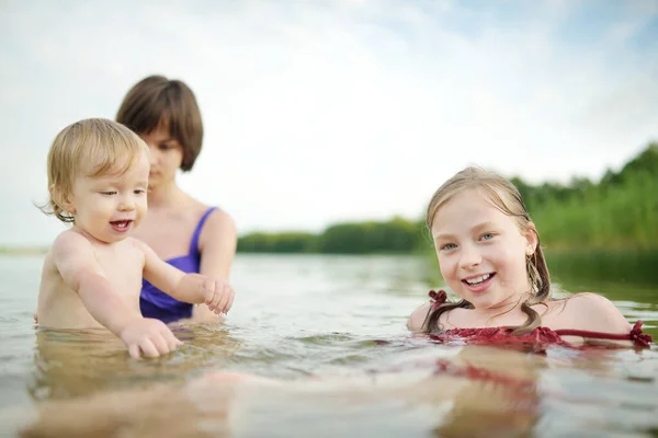 かわいい幼児の男の子と暑い夏の日に川で遊んでいる彼の大きな十代の姉妹 夏の休暇中に屋外で楽しい時間を過ごしている愛らしい子供 子供のための水活動 — ストック写真