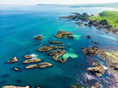 County Antrim Causeway Coast boyunca Ballintoy limanında canlı zümrüt yeşili su. Kuzey İrlanda'nın engebeli kıyı manzarası.