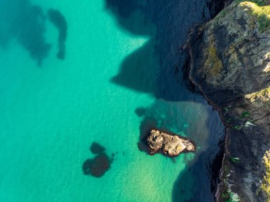 County Antrim Causeway Coast boyunca Ballintoy limanında canlı zümrüt yeşili su. Kuzey İrlanda'nın engebeli kıyı manzarası.
