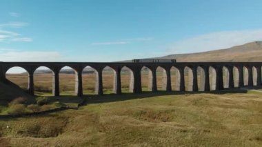 Trenin Ribblehead viyadüğü boyunca giden hava görüntüsü Settle-Carlisle hattındaki en uzun ve en uzun üçüncü yapı. İngiltere 'deki Yorkshire Dales Ulusal Parkı' nda turistik etkinlikler
