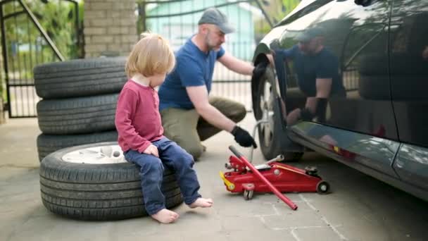 Słodki Chłopiec Maluch Pomaga Ojcu Zmienić Koła Samochodu Ich Podwórku — Wideo stockowe