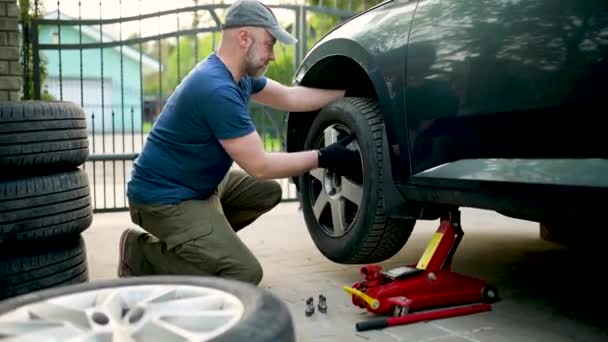 남자가 뜰에서 자동차 바퀴를 바꾸고 기술자는 타이어를 수리하기 도구를 — 비디오
