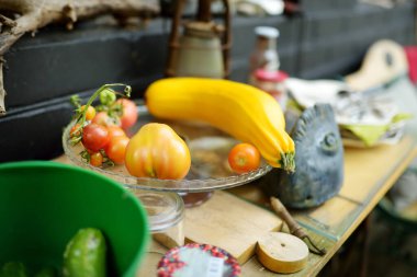 Açık mutfak rafında sarı kabaklı ve domatesli cam tabak.