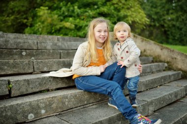 Komik çocuk ve ablası güneşli bir sonbahar gününde dışarıda eğleniyorlar. Doğayı keşfeden çocuklar. Şehir parkında yürüyen çocuklar. Küçük çocuklar için sonbahar aktiviteleri.