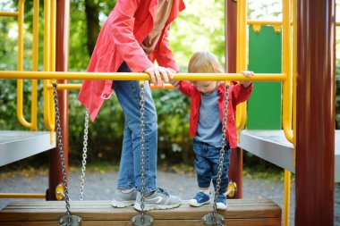Küçük tatlı bir çocuk, sıcak bir sonbahar gününde oyun parkında ablasıyla eğleniyor. Sonbaharda çocuklar için aktif eğlence.
