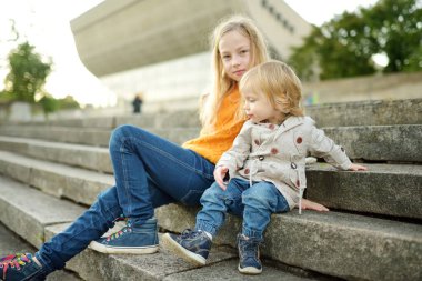Komik çocuk ve ablası güneşli bir sonbahar gününde dışarıda eğleniyorlar. Doğayı keşfeden çocuklar. Şehir parkında yürüyen çocuklar. Küçük çocuklar için sonbahar aktiviteleri.