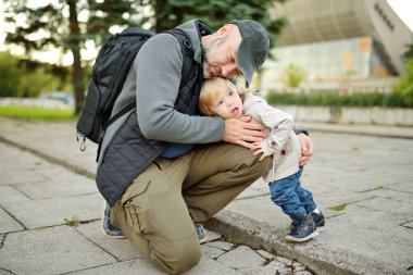 Babasının kollarında tatlı bir çocuk var. Baba ve oğul güneşli bir sonbahar gününde eğleniyorlar. Sevimli oğlu babası tarafından tutuluyor.