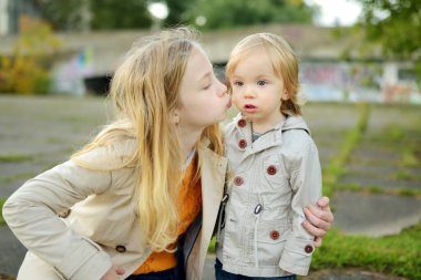 Komik çocuk ve ablası güneşli bir sonbahar gününde dışarıda eğleniyorlar. Doğayı keşfeden çocuklar. Şehir parkında yürüyen çocuklar. Küçük çocuklar için sonbahar aktiviteleri.