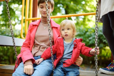 Küçük tatlı bir çocuk, sıcak bir sonbahar gününde oyun parkında ablasıyla eğleniyor. Sonbaharda çocuklar için aktif eğlence.