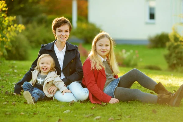 Two big sisters and their little brother having fun outdoors. Two young girls holding toddler boy on autumn day. Children with large age gap. Big age difference between siblings. Big family.