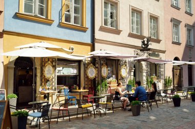 WARsaw, POLAND - Ağustos 2021: Turistler İkinci Dünya Savaşı sırasında tamamen yıkılan ve 1949-1953 yılları arasında yeniden inşa edilen Eski Şehrin güzel sokaklarını keşfediyorlar. Güneşli yaz günü.