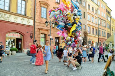 WARsaw, POLAND - Ağustos 2021: Turistler İkinci Dünya Savaşı sırasında tamamen yıkılan ve 1949-1953 yılları arasında yeniden inşa edilen Eski Şehrin güzel sokaklarını keşfediyorlar. Güneşli yaz günü.