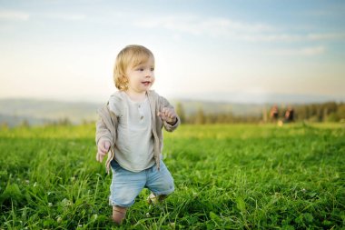 Komik çocuk güneşli yaz gününde dışarıda eğleniyor. Doğayı keşfeden çocuk. Yazın veya ilkbaharda yüksek dağlar ve yeşil tepeler. Polonya 'da manzara dağ manzarası.