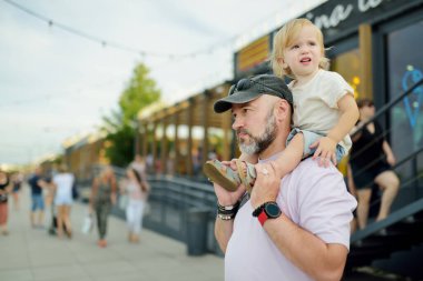 Baba ve küçük oğlu Varşova 'nın eski şehrinin güzel sokaklarını keşfediyorlar. Baba kucağında küçük oğlunu tutuyor. Aile yazın yürür..