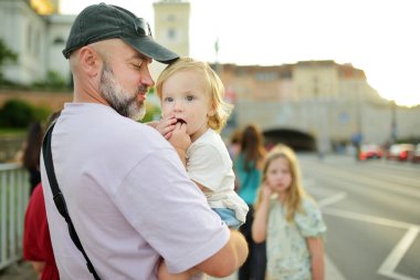 Baba ve küçük oğlu Varşova 'nın eski şehrinin güzel sokaklarını keşfediyorlar. Baba kucağında küçük oğlunu tutuyor. Aile yazın yürür..
