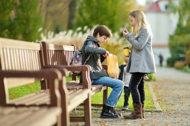 İki tatlı genç kız kardeş ve yeni yürümeye başlayan erkek kardeşleri güzel bir sonbahar gününde parkta piknik yapıyorlar. Çocuklarla aktif aile eğlencesi. Aile eğlencesi..