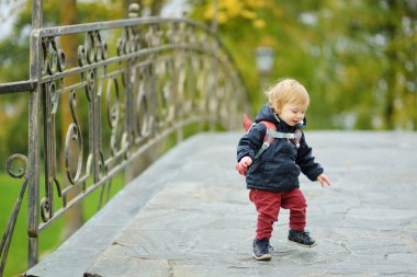 Komik çocuk güneşli bir sonbahar gününde dışarıda eğleniyor. Doğayı keşfeden çocuk. Şehir parkında oynayan bir çocuk. Küçük çocuklar için sonbahar aktiviteleri.