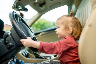 Sürücü koltuğunda oynayan sevimli küçük çocuk. Babasının arabasında oturan tatlı küçük oğlu. Küçük çocuk arabada eğleniyor..