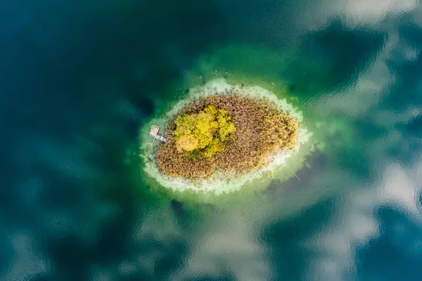 小さな島の空中トップダウンビュー 松林に囲まれたゲラ湖の美しい緑の海の鳥の目 リトアニア ビリニュス市付近のゲラ湖に反射する雲 — ストック写真