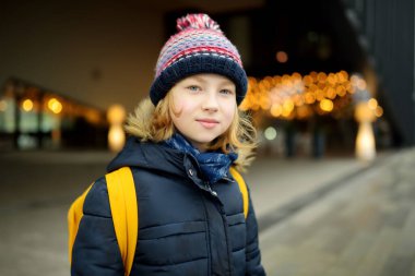 Soğuk kış sabahında sırt çantalı tatlı bir kız okula gidiyor. Çocuk okula geri dönüyor. Çocuklar için eğitim.