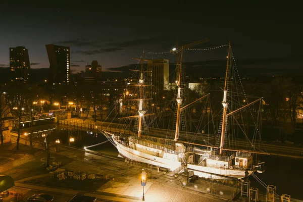 Aerial view of Meridianas sailing ship, one of the most recognisable landmarks of Klaipeda, a docked boat featuring genteel riverside restaurant. Nightlife of Klaipeda, Lithuania.