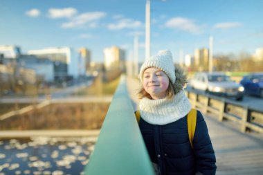 Soğuk kış sabahında sırt çantalı tatlı bir kız okula gidiyor. Çocuk okula geri dönüyor. Çocuklar için eğitim.