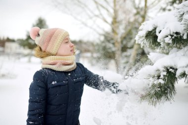 Serin kış günlerinde karla kaplı parkta yürüyüş yapan tatlı genç kız. Doğayı keşfeden çocuk. Çocuklar için kış aktiviteleri.