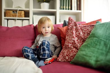 Kırmızı oyuncak arabayla oynayan tatlı bir çocuk. Küçük çocuk oyuncaklarla eğleniyor. Çocuk evdeki sıcak bir oturma odasında vakit geçiriyor. Evde aile eğlencesi..