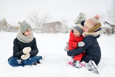 İki tatlı genç kız ve küçük erkek kardeşleri serin kış günlerinde karla kaplı parkta eğleniyorlardı. Doğayı keşfeden çocuklar. Çocuklar için kış aktiviteleri.