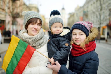 İki abla ve onların sevimli küçük erkek kardeşleri Litvanya 'nın Bağımsızlık Günü' nü kutluyorlar. Litvanya, Vilnius 'ta üç renkli Litvanya bayrağı taşıyan çocuklar.