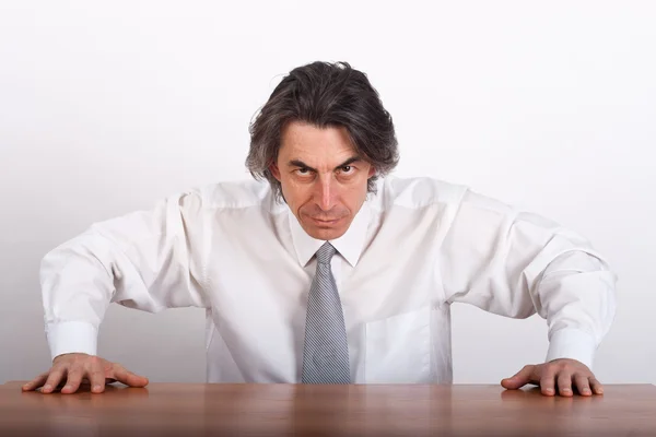 Hombre de negocios enojado sentado a la mesa . — Foto de Stock