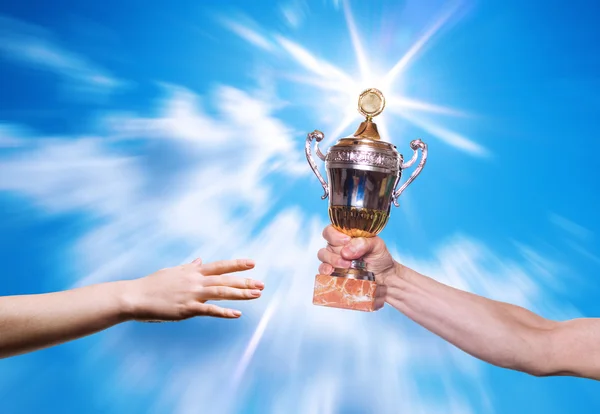 Hands of the person with a sports cup on a background of the bright sky. — Stock Photo, Image