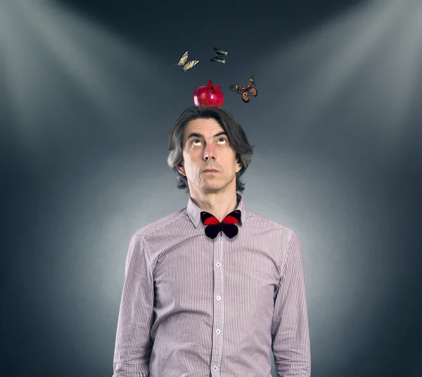Um homem com uma maçã na cabeça e borboletas voadoras . — Fotografia de Stock