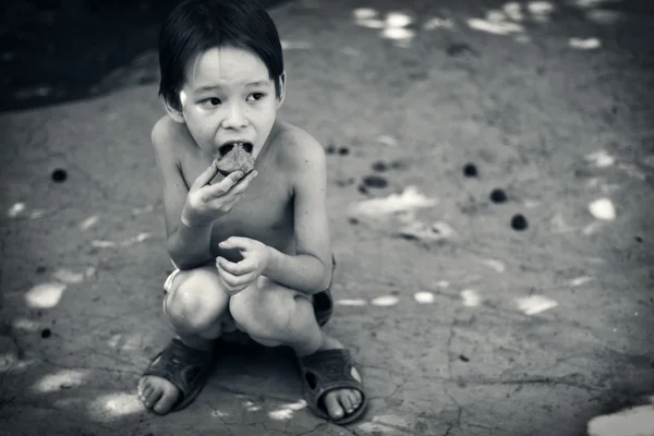 Samotny chłopiec głodny zjada siedzi na ziemi — Zdjęcie stockowe