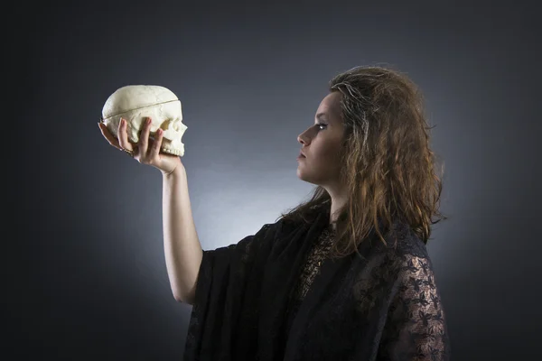 Witch casts a spell with a skull — Stock Photo, Image